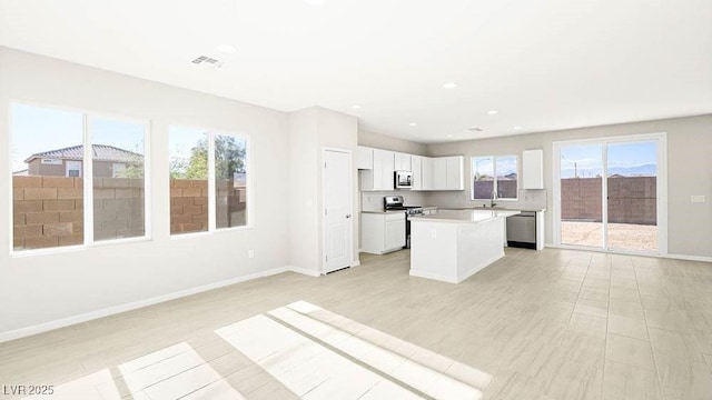 kitchen featuring a kitchen island, tasteful backsplash, sink, white cabinets, and stainless steel appliances