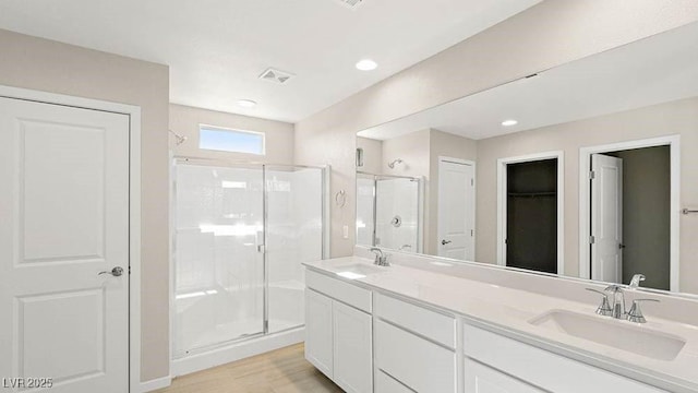 bathroom with hardwood / wood-style flooring, vanity, and a shower with shower door