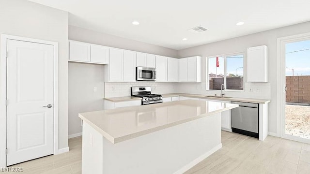 kitchen with white cabinetry, sink, stainless steel appliances, and a kitchen island