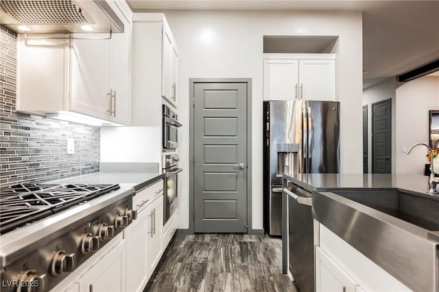 kitchen featuring sink, exhaust hood, dark hardwood / wood-style floors, stainless steel appliances, and white cabinets