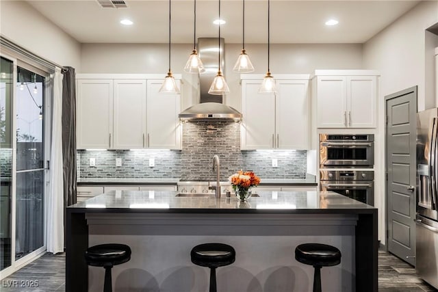 kitchen with white cabinetry, tasteful backsplash, a kitchen island with sink, and hanging light fixtures