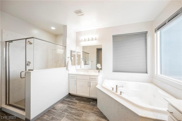 bathroom with independent shower and bath, vanity, and a healthy amount of sunlight