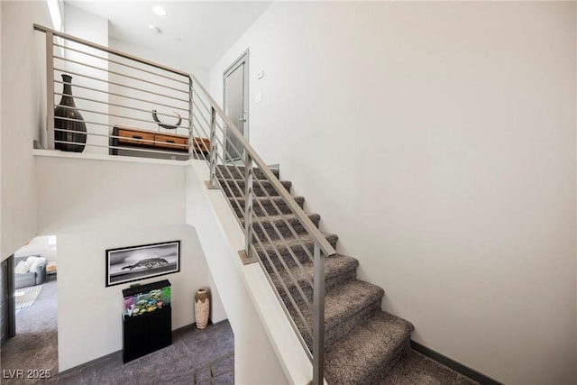 stairway featuring a high ceiling and carpet floors