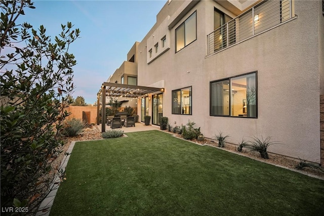 back house at dusk with a patio, a lawn, and a pergola