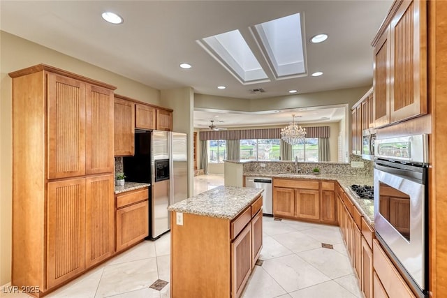 kitchen featuring appliances with stainless steel finishes, sink, hanging light fixtures, a center island, and kitchen peninsula