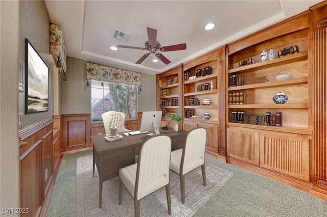 office area featuring light carpet, ceiling fan, and built in shelves