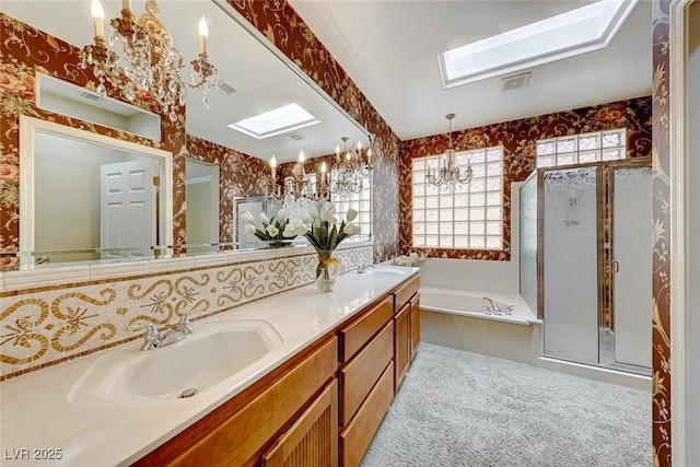 bathroom with vanity, shower with separate bathtub, a skylight, and a notable chandelier