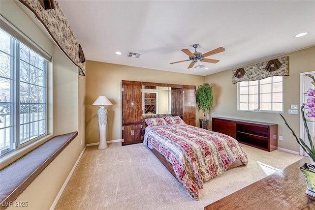 bedroom featuring multiple windows, light colored carpet, and ceiling fan