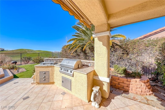 view of patio with an outdoor kitchen, a grill, and a mountain view