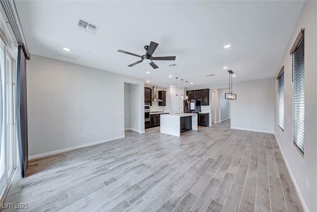 unfurnished living room with sink, ceiling fan, and light hardwood / wood-style flooring