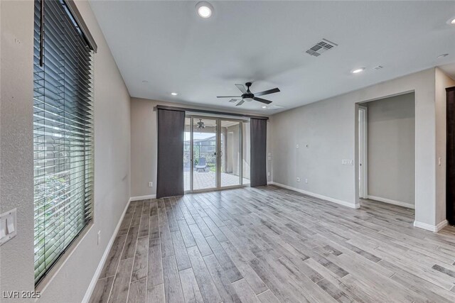 empty room with ceiling fan and light hardwood / wood-style floors