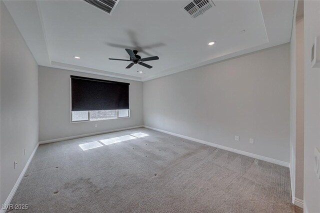 carpeted empty room featuring ceiling fan and a raised ceiling