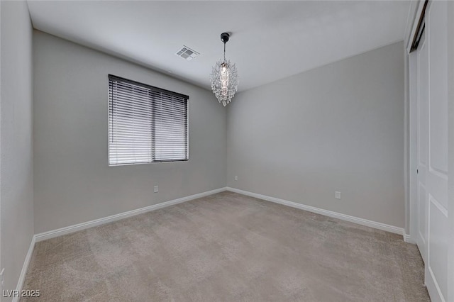 unfurnished room with light carpet and a chandelier