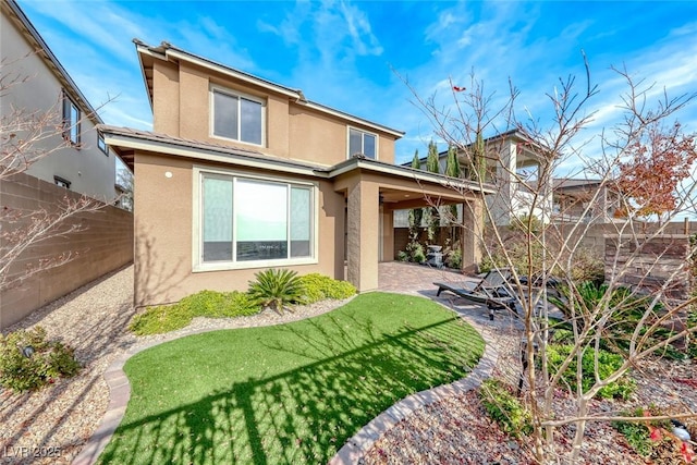 rear view of house with a patio and a lawn