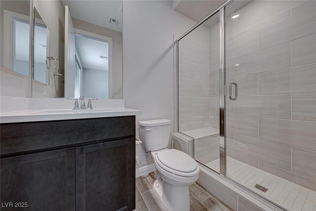 bathroom with vanity, toilet, and a shower with door