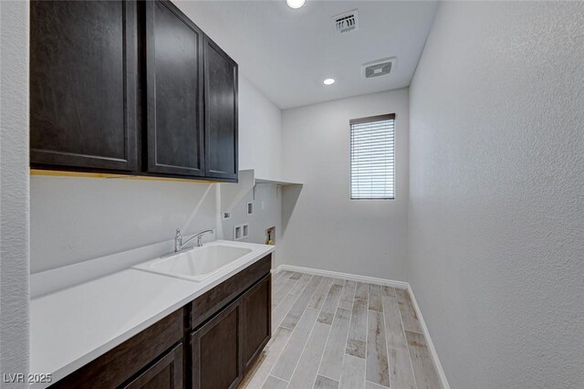 laundry area featuring sink, cabinets, light wood-type flooring, hookup for a washing machine, and hookup for an electric dryer