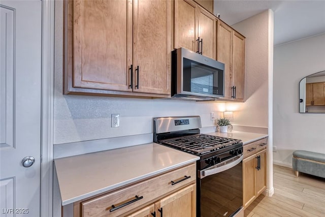 kitchen featuring light wood-type flooring, light brown cabinets, and appliances with stainless steel finishes