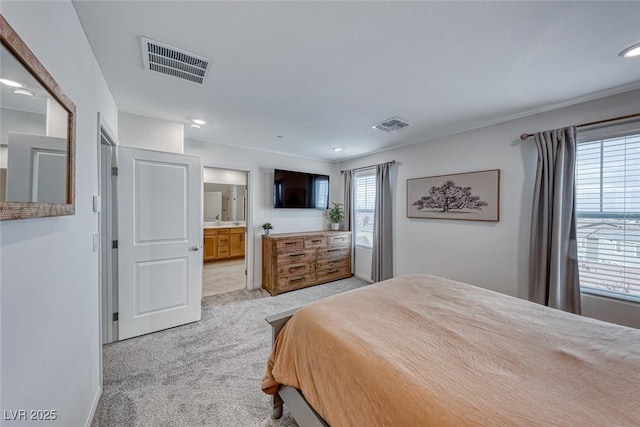 bedroom featuring light colored carpet and ensuite bath