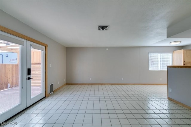 tiled empty room featuring french doors