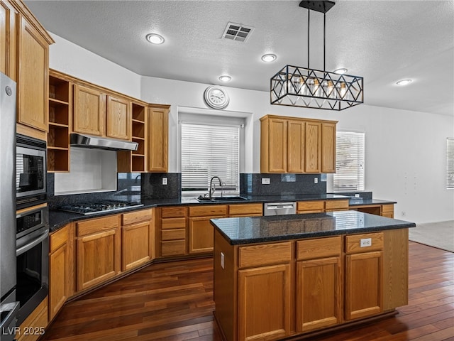 kitchen featuring sink, appliances with stainless steel finishes, a kitchen island, pendant lighting, and backsplash