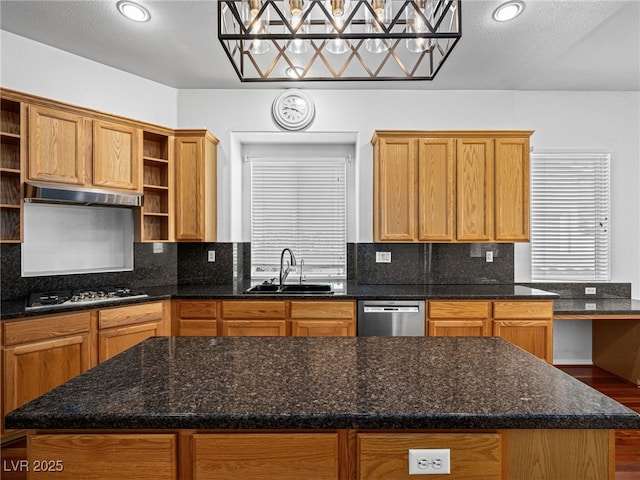 kitchen featuring sink, gas stovetop, dark stone countertops, stainless steel dishwasher, and a kitchen island