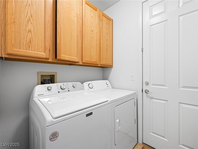 clothes washing area featuring cabinets and separate washer and dryer