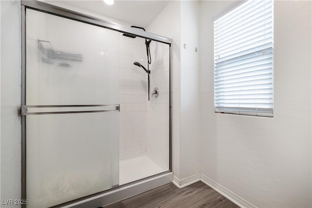 bathroom with hardwood / wood-style flooring, plenty of natural light, and a shower with door