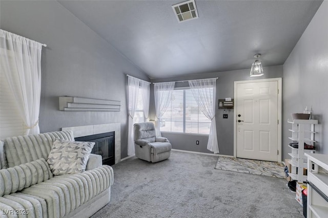 carpeted living room with a tile fireplace and lofted ceiling