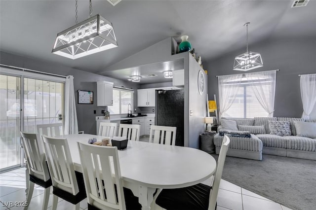 dining area featuring light tile patterned flooring, lofted ceiling, and an inviting chandelier