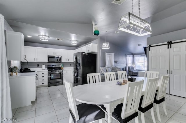 tiled dining space with a barn door, sink, and lofted ceiling