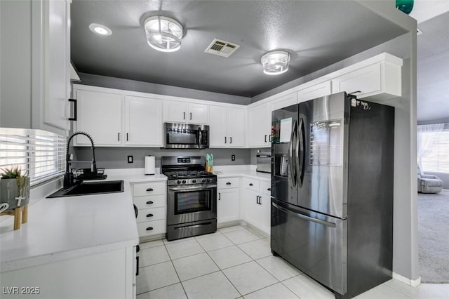 kitchen with white cabinetry, stainless steel appliances, sink, and light tile patterned floors