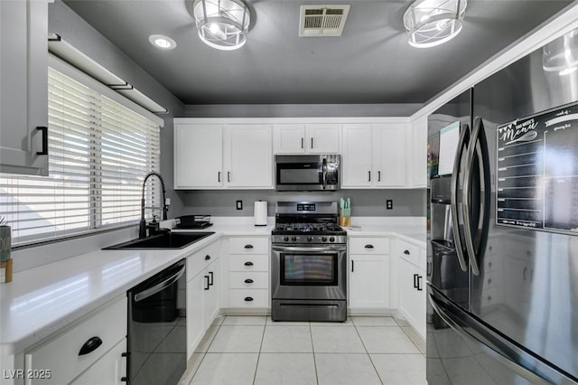 kitchen with sink, light tile patterned floors, white cabinets, and appliances with stainless steel finishes