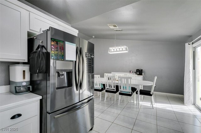 kitchen featuring decorative light fixtures, white cabinetry, lofted ceiling, light tile patterned floors, and stainless steel fridge with ice dispenser