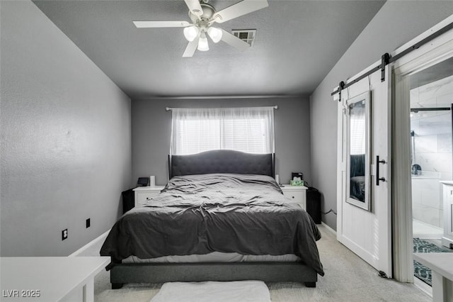 carpeted bedroom with a textured ceiling, a barn door, and ceiling fan