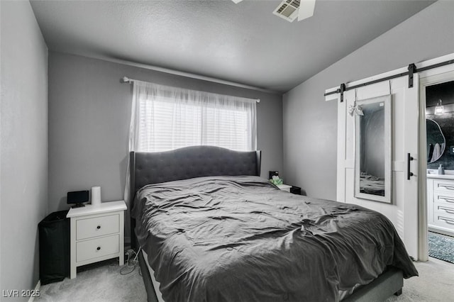 bedroom with lofted ceiling, light colored carpet, and a barn door