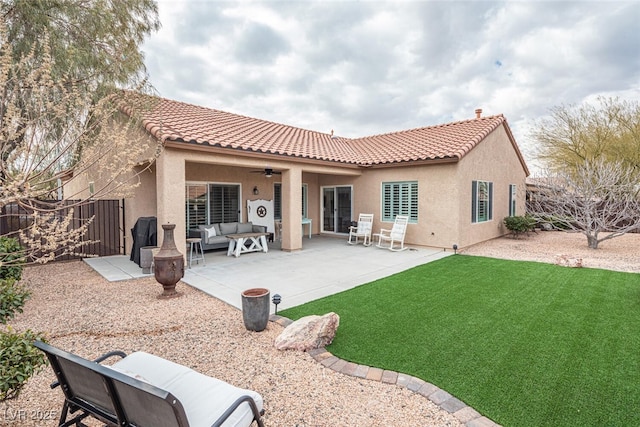 back of property with a patio area, outdoor lounge area, ceiling fan, and a lawn