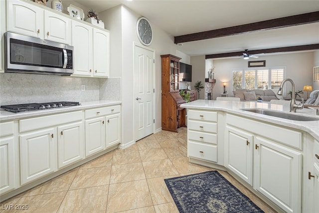 kitchen featuring sink, beam ceiling, stainless steel appliances, tasteful backsplash, and white cabinets