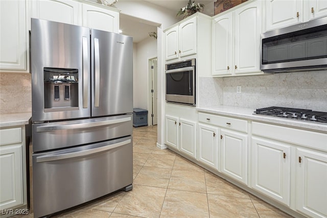 kitchen with backsplash, light tile patterned floors, stainless steel appliances, and white cabinets