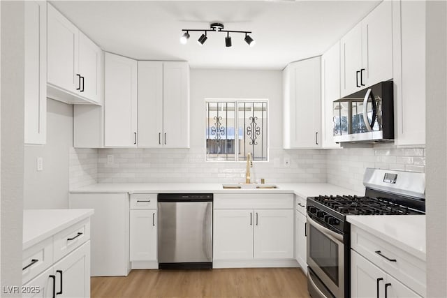 kitchen featuring tasteful backsplash, appliances with stainless steel finishes, sink, and white cabinets