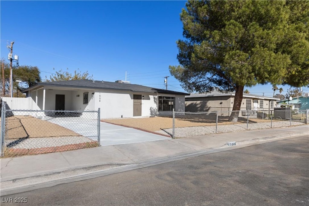 view of front of house with concrete driveway, an attached carport, a fenced front yard, and stucco siding