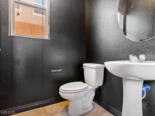 bathroom featuring a textured wall, tile patterned flooring, plenty of natural light, and toilet