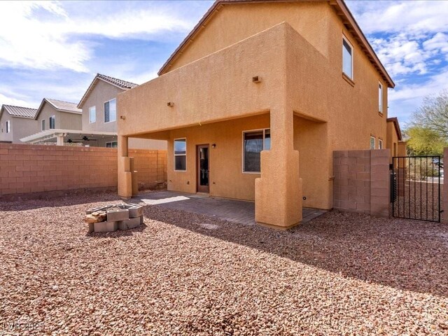 rear view of house with fence, a patio, and stucco siding