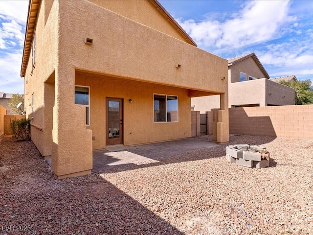 back of house with an outdoor fire pit, a patio area, and stucco siding