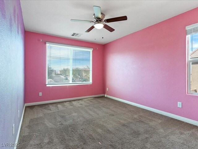 carpeted empty room with a ceiling fan, visible vents, and baseboards