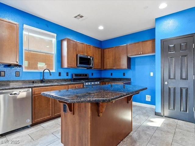 kitchen with visible vents, a center island, stainless steel appliances, a kitchen bar, and a sink