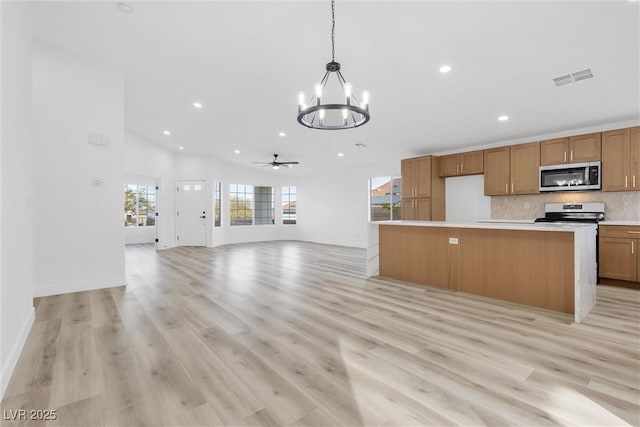 kitchen featuring lofted ceiling, a center island, hanging light fixtures, light wood-type flooring, and stainless steel appliances