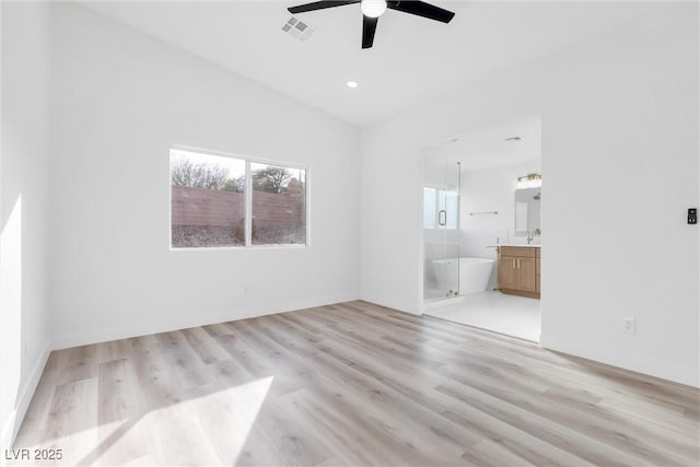 interior space with ceiling fan, lofted ceiling, sink, and light wood-type flooring