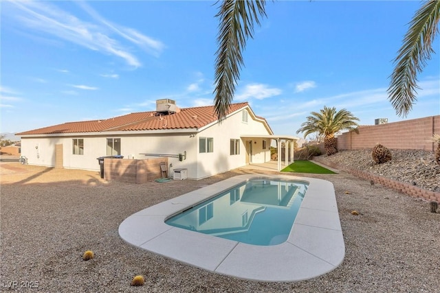 back of property featuring a swimming pool with hot tub, central AC unit, and a patio area