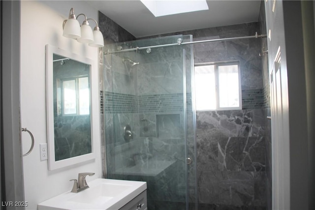 bathroom featuring an enclosed shower, vanity, and a skylight