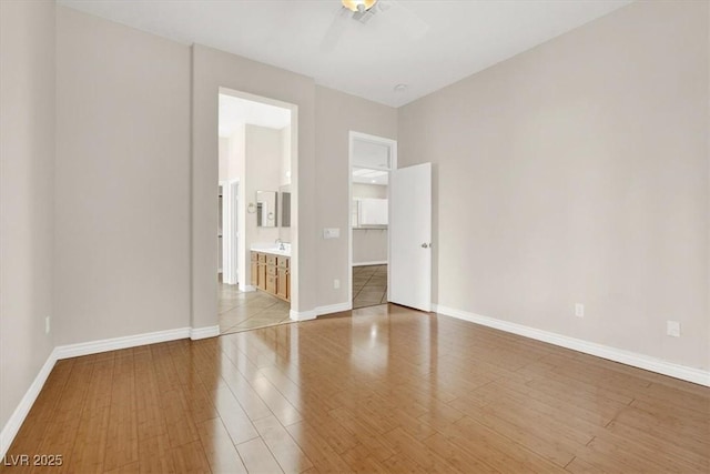 unfurnished bedroom featuring light hardwood / wood-style flooring, ensuite bath, and a spacious closet